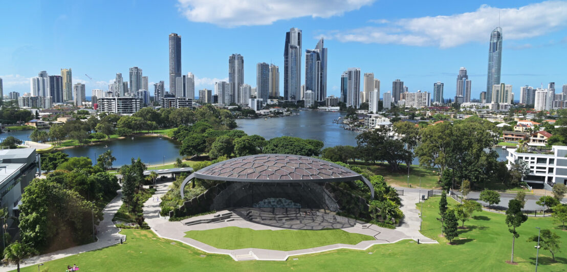 Modernes, muschelförmiges Kulturzentrum mit Parkanlage an einem See vor der Skyline von Surfers Paradise.