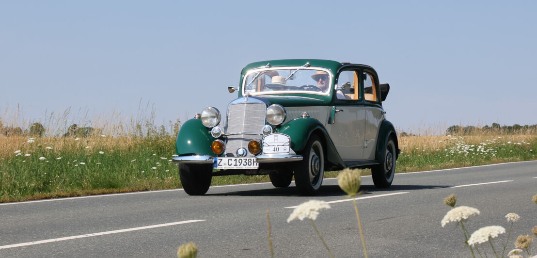 Ein grüner Mercedes-Benz Cabriolet Oldtimer mit H-Kennzeichen fährt auf einer Landstraße.