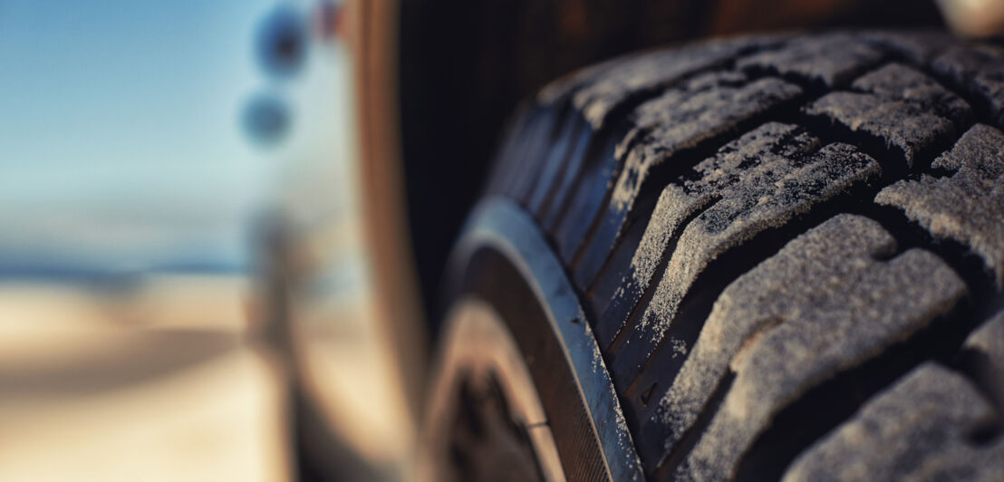 Nahaufnahme eines Autoreifens mit Sand auf dem Profil.