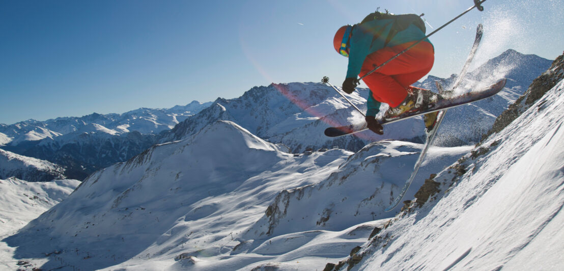 Mann beim Freeriding in Ischgl vor einer sonnigen, verschneiten Bergkulisse.