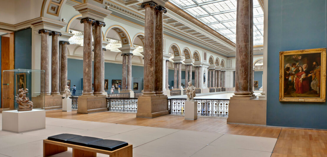 Galerie in einem historischen Museumsgebäude mit Marmorsäulen und Glaskuppel.