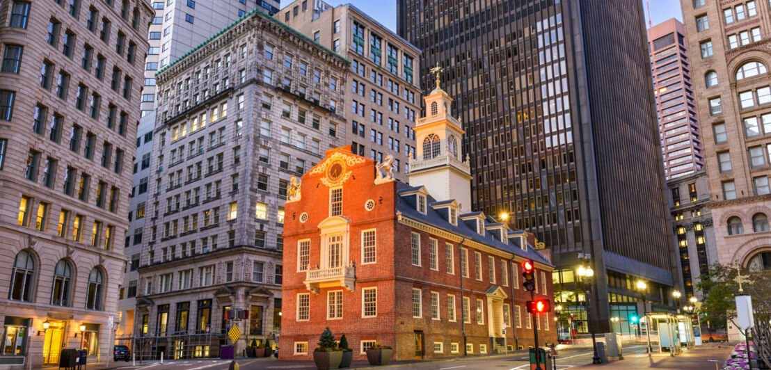 Kreuzung in Boston vor dem Old State House bei Dämmerung mit hohen Gebäuden im Hintergrund.