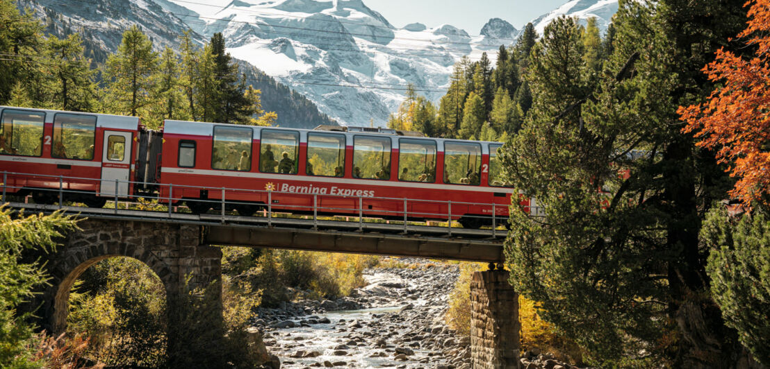 in roter Panoramazug auf einer Brücke in einer Berglandschaft.