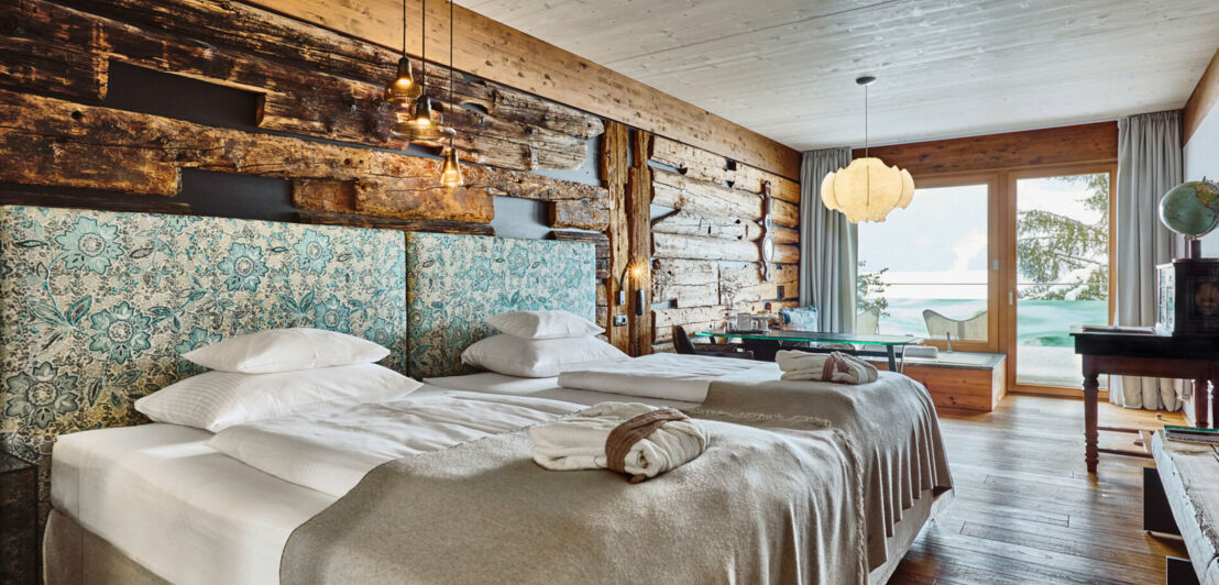 Helles Hotelzimmer mit Holzverkleidung im Chalet-Stil und zwei Doppelbetten.