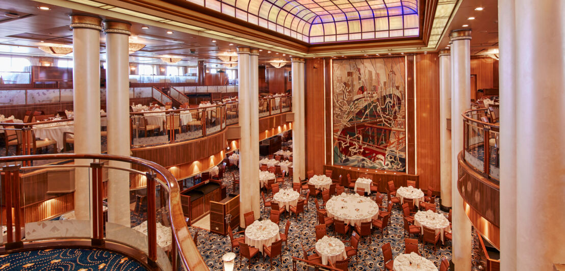 Nobles zweistöckiges Restaurant mit Jugendstil-Dekor und weiß eingedeckten Tischen.