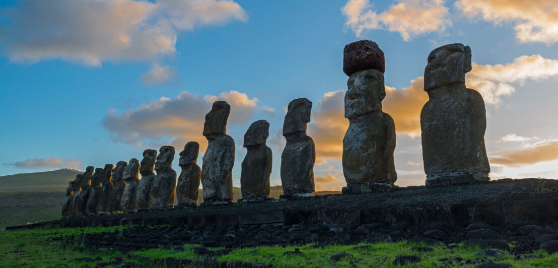 Eine Reihe von Moai-Steinfiguren auf der Osterinsel bei Sonnenaufgang.