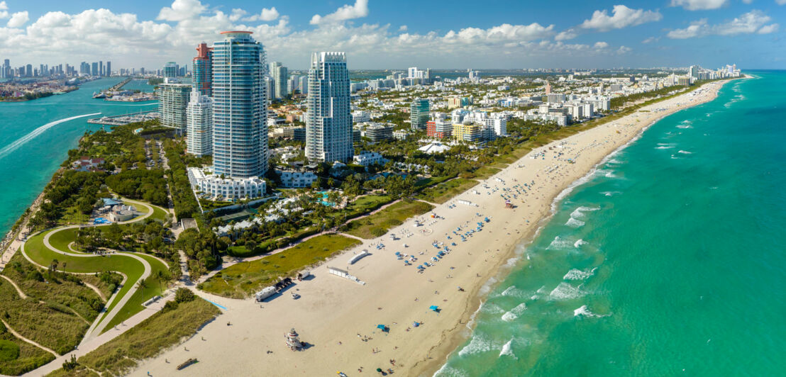 Skyline von Miami Beach mit breitem Sandstrand am türkisblauen Meer bei Sonnenschein.