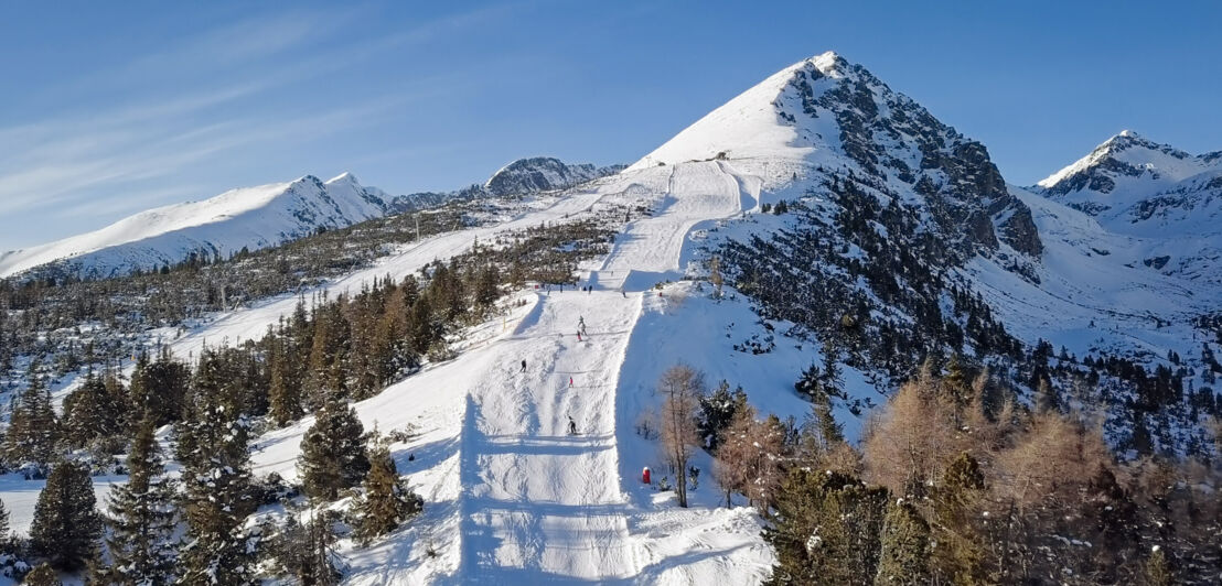 Personen auf einer Skipiste auf einem Berg.