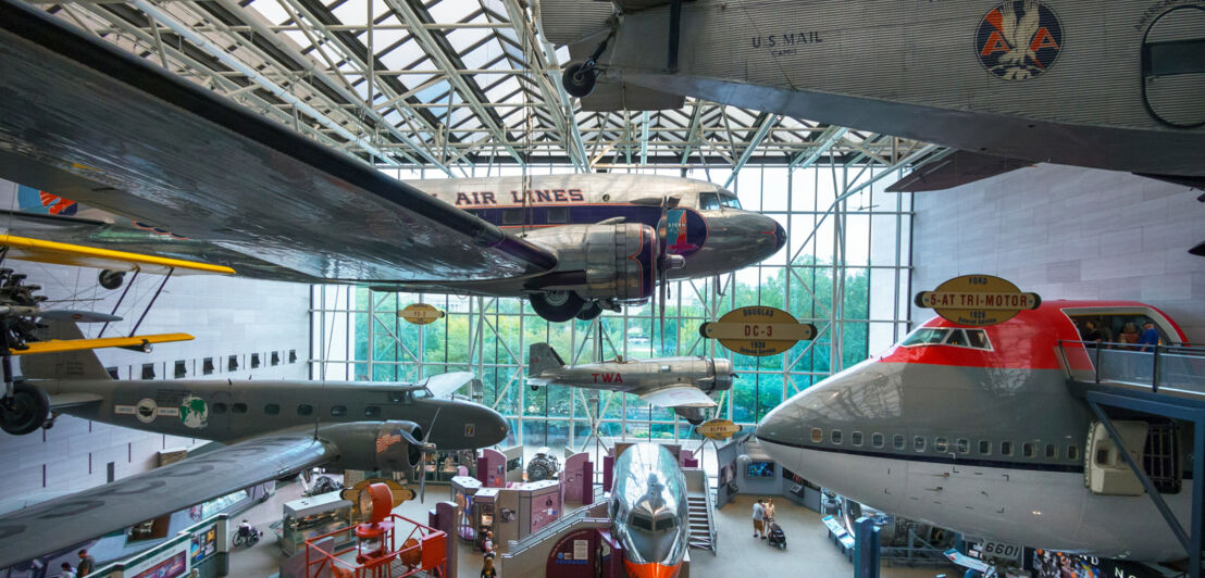 Ausstellungsraum mit historischen Flugzeugen, die teilweise von der Decke hängen.