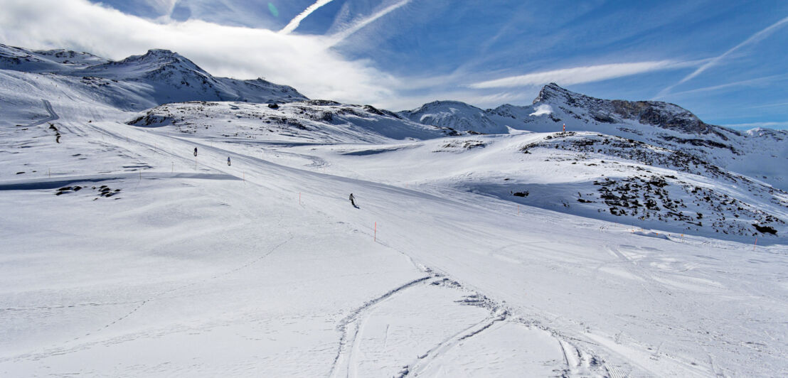 Blick auf ein Skigebiet in den Bergen bei blauem Himmel. 