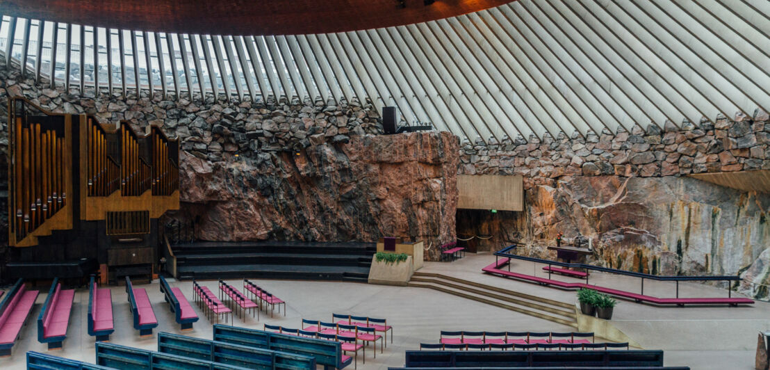 Altarraum mit Orgel in einer modernen Kirche mit Granitfelswand.