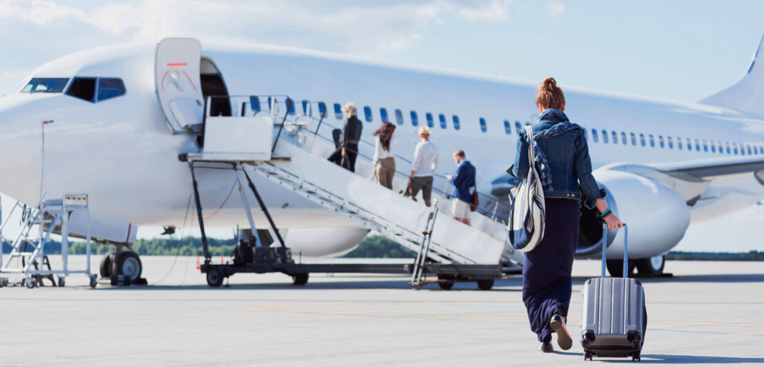 Personen in Reihe mit Handgepäck auf dem Rollfeld beim Boarding. Personen in Reihe mit Handgepäck auf dem Rollfeld beim Boarding.