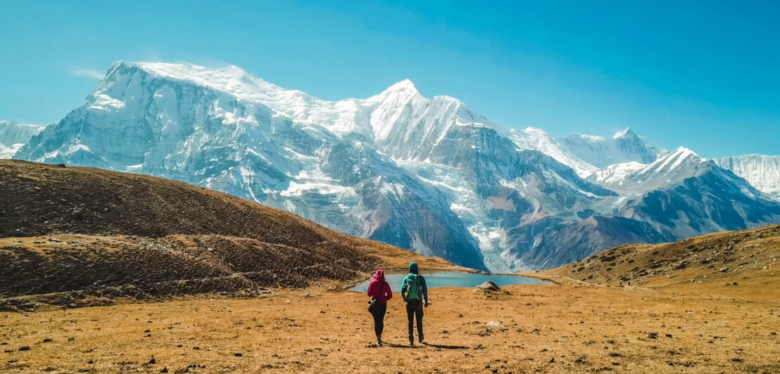 Zwei Personen auf einer Hochebene vor schneebedeckten Gipfeln des Himalayas. Zwei Personen auf einer Hochebene vor schneebedeckten Gipfeln des Himalayas.