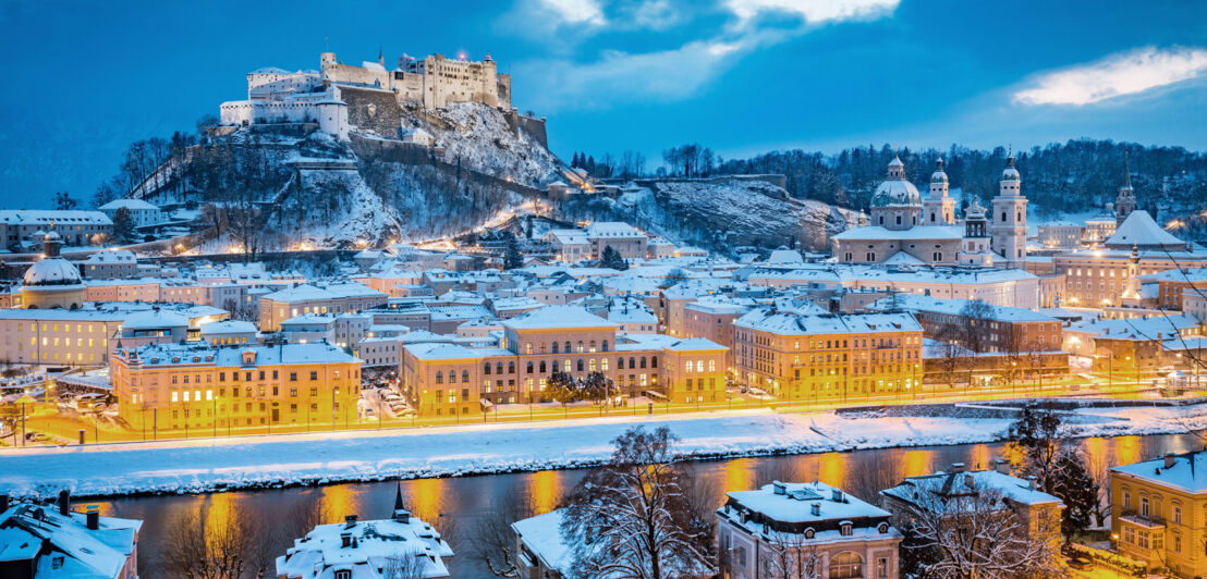 Schneebedecktes Stadtpanorama von Salzburg mit beleuchteten Straßen bei Dunkelheit. Schneebedecktes Stadtpanorama von Salzburg mit beleuchteten Straßen bei Dunkelheit.