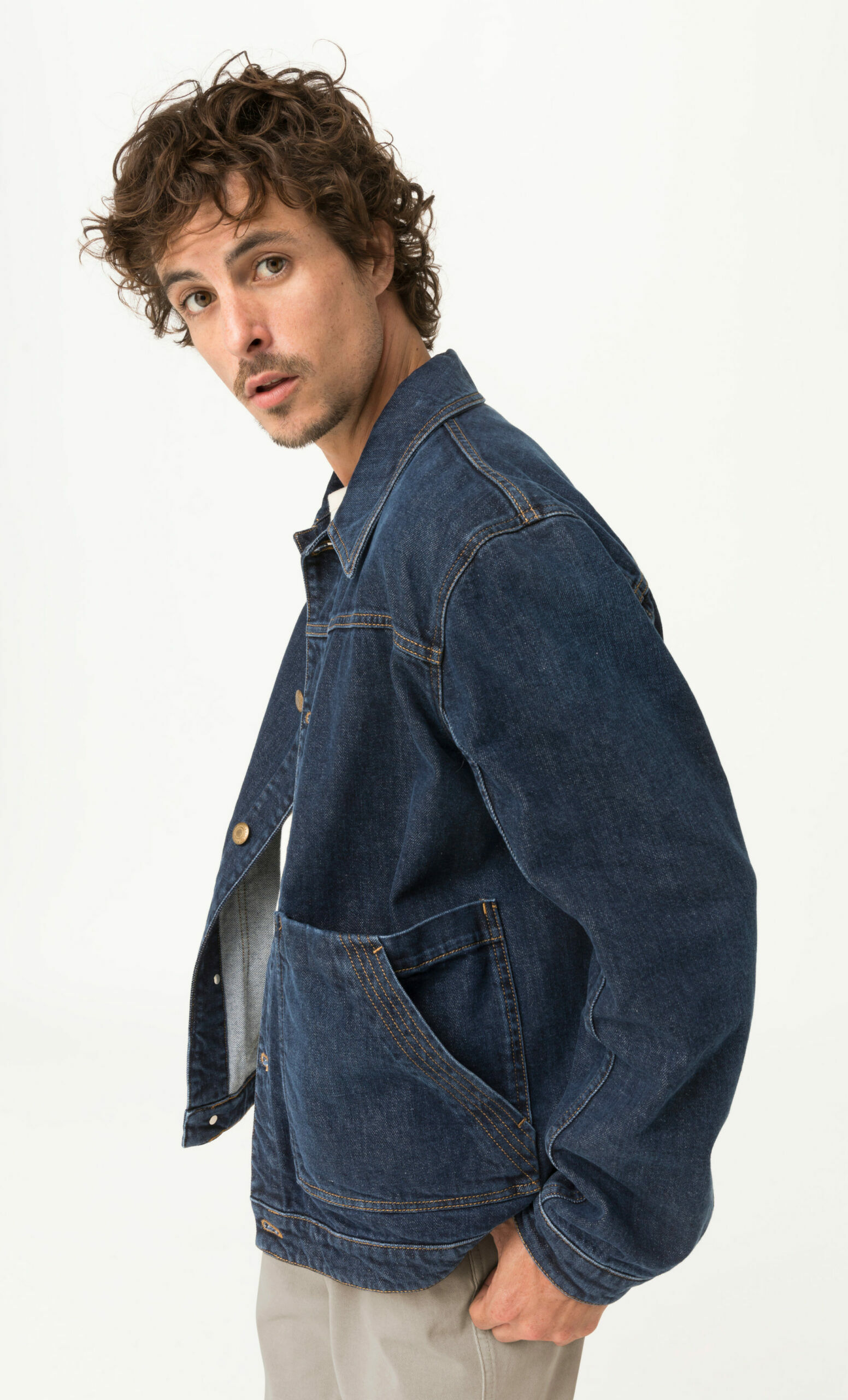 Model in Jeansjacke aus dunkelblauem Denim mit schrägen Taschen, Studioaufnahme