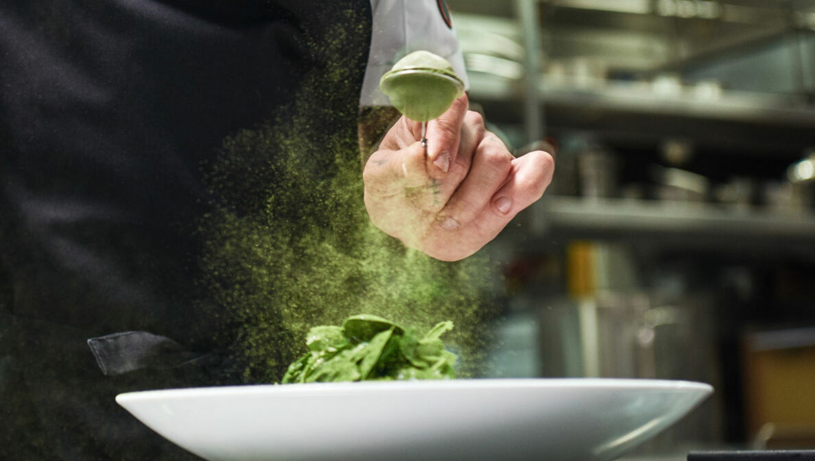 Koch würzt Gericht mit Matcha in Restaurantküche