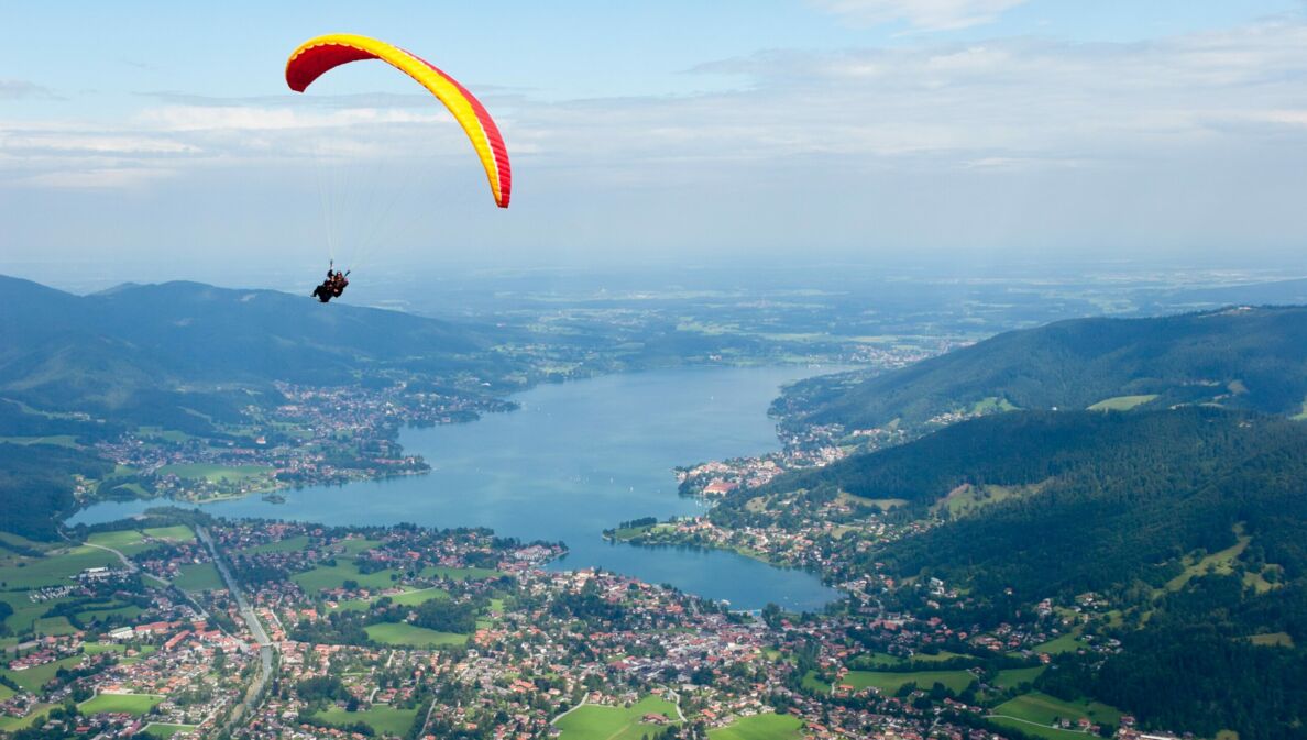 Gleitschirmflieger mit Blick von oben auf den Tegernsee