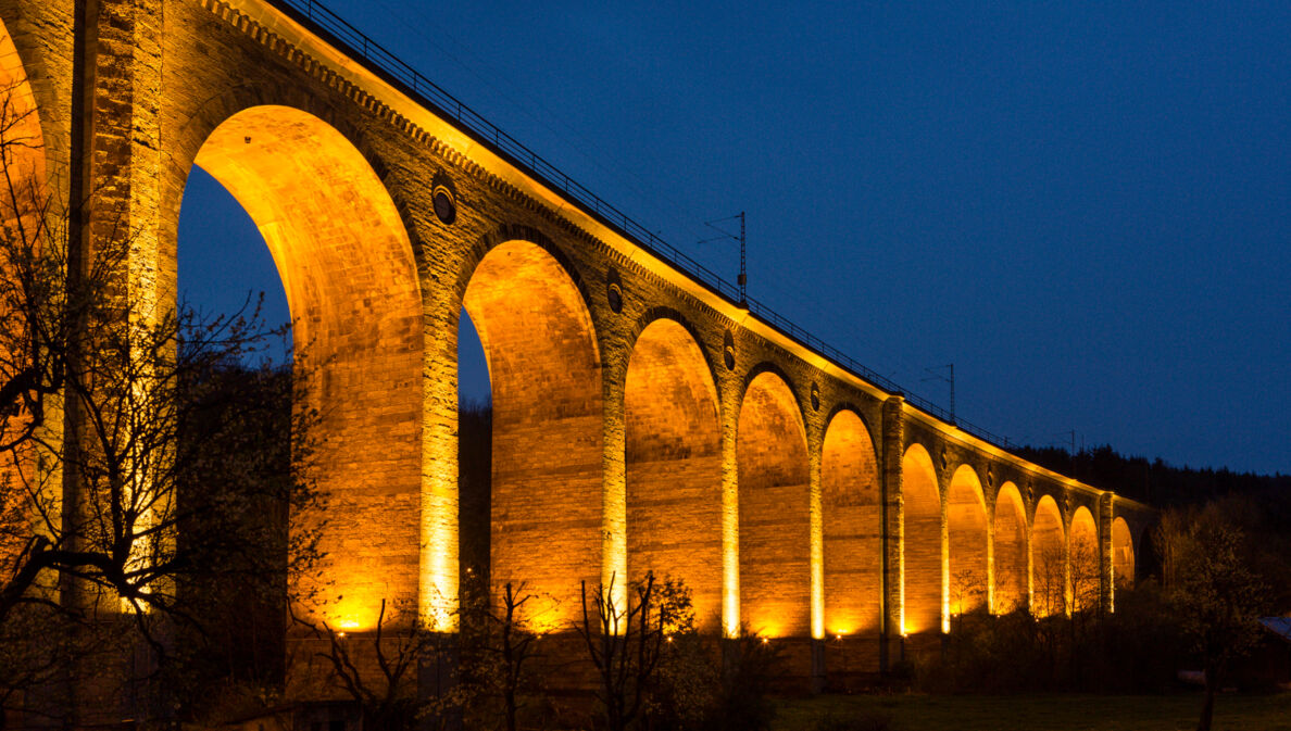 Hell beleuchtetes Viadukt bei Dunkelheit