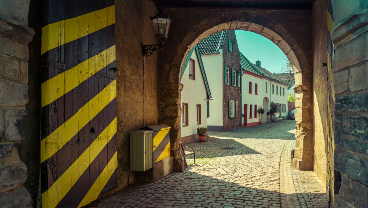 Ein historisches Stadttor mit gelb-schwarz gestreifter Tür