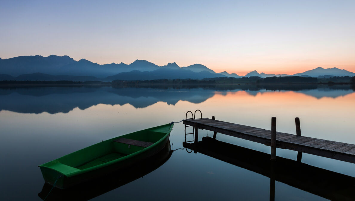 Der See Hopfen in den Bayerischen Alpen mit Boot und Steg bei Dämmerung