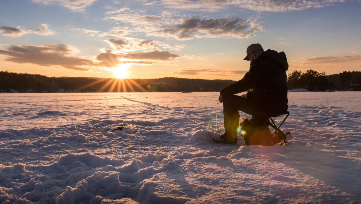 Ein Eisangler sitzt auf einem zugefrorenen See