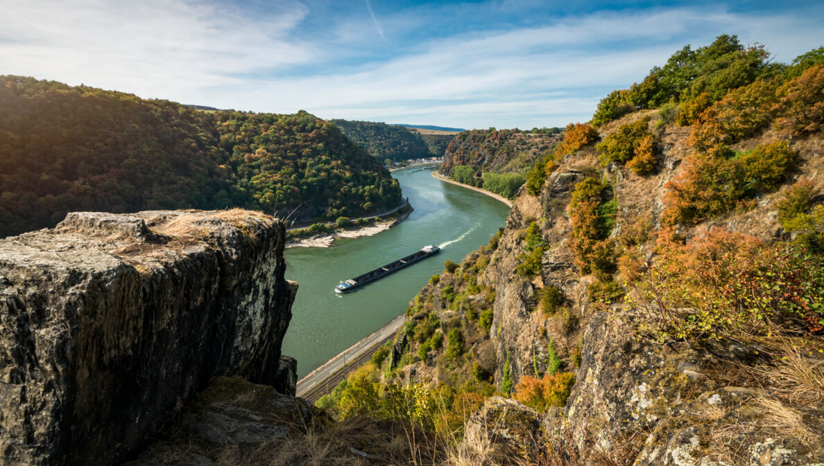 Panoramablick auf Rheinkurve mit Containerschiff von einem Plateau in felsiger Umgebung