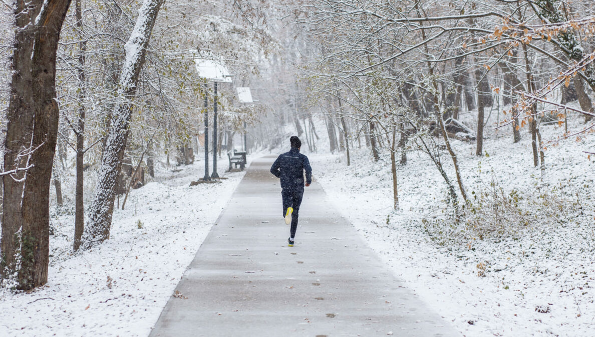 Mann von hinten fotografiert beim Joggen durch eine Winterlandschaft