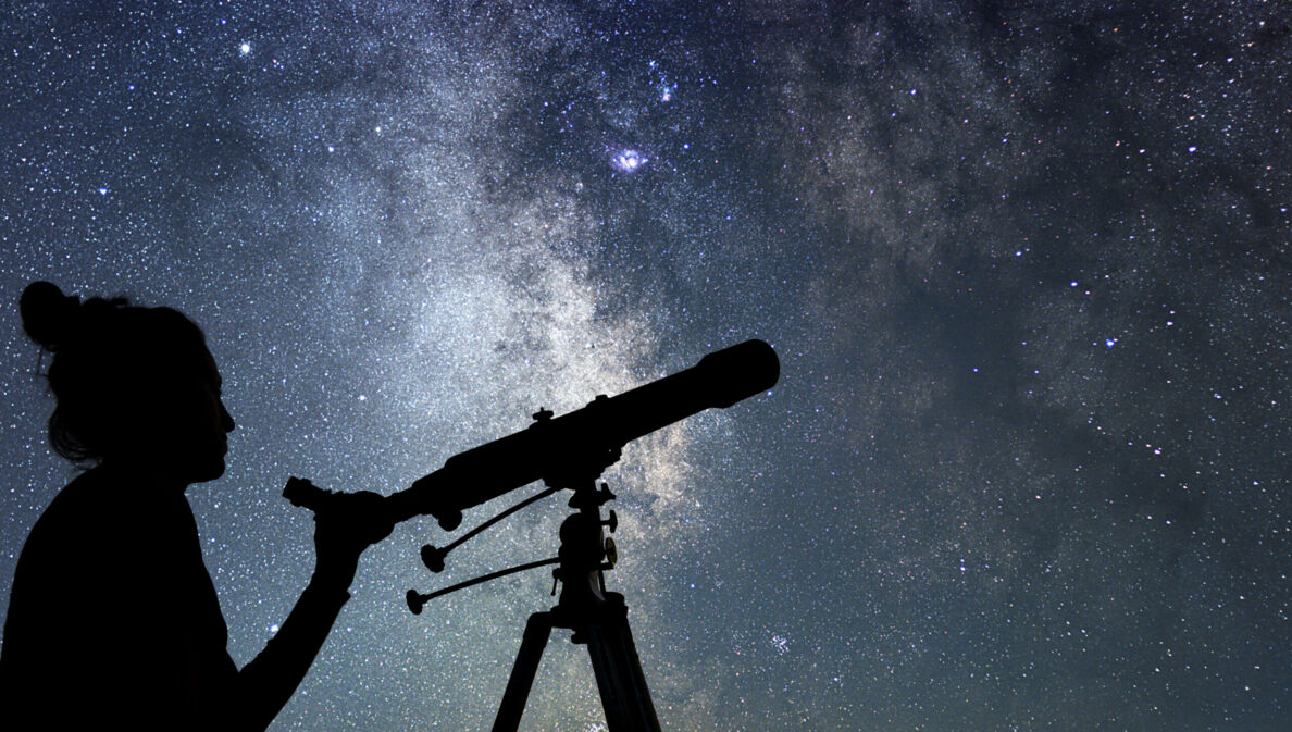 Eine Frau mit Teleskop vor Sternenhimmel.