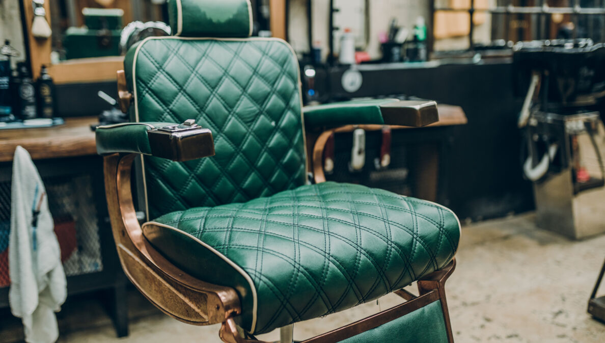 Ein Vintage-Barbersessel mit grünem Lederbezug in einem Barbershop