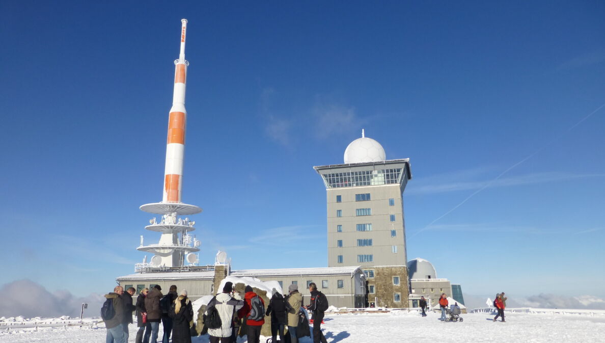 Eine Gruppe Touristen auf dem Gipfel des Brocken im Winter.