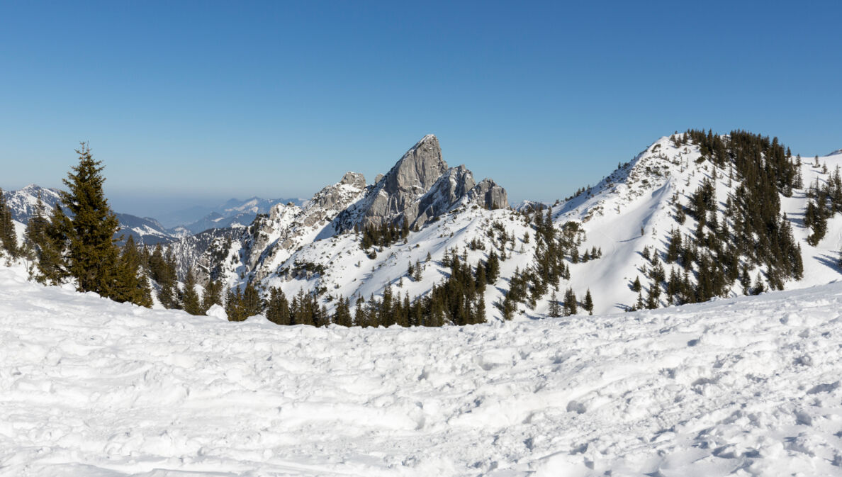 Blick auf die teilweise verschneiten Gipfel des Mangfallgebirges bei blauem Himmel