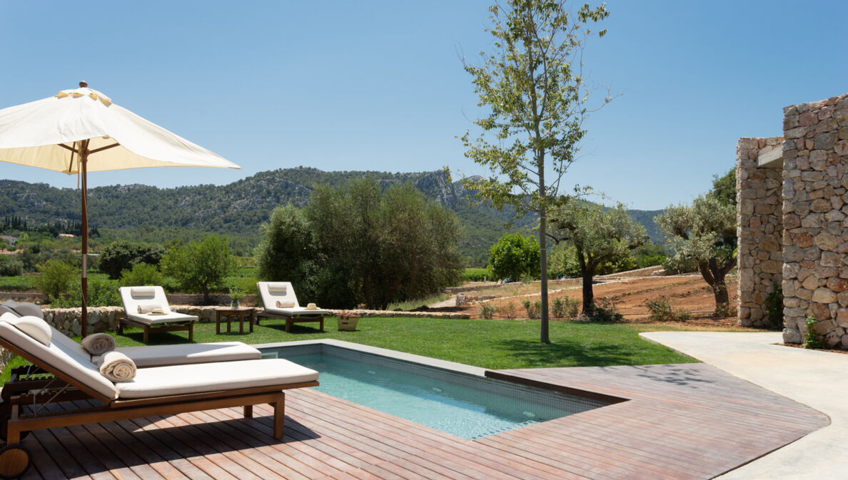 Ein kleiner Pool und Sonnenliegen vor einer bergigen Landschaft