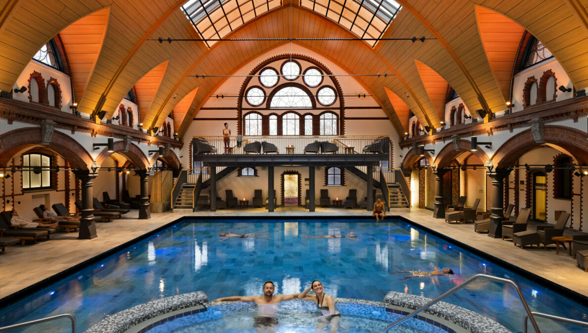 Innenraumansicht einer Schwimmhalle mit Saunalandschaft und Whirlpool im historischen Gebäude mit Kuppeldach