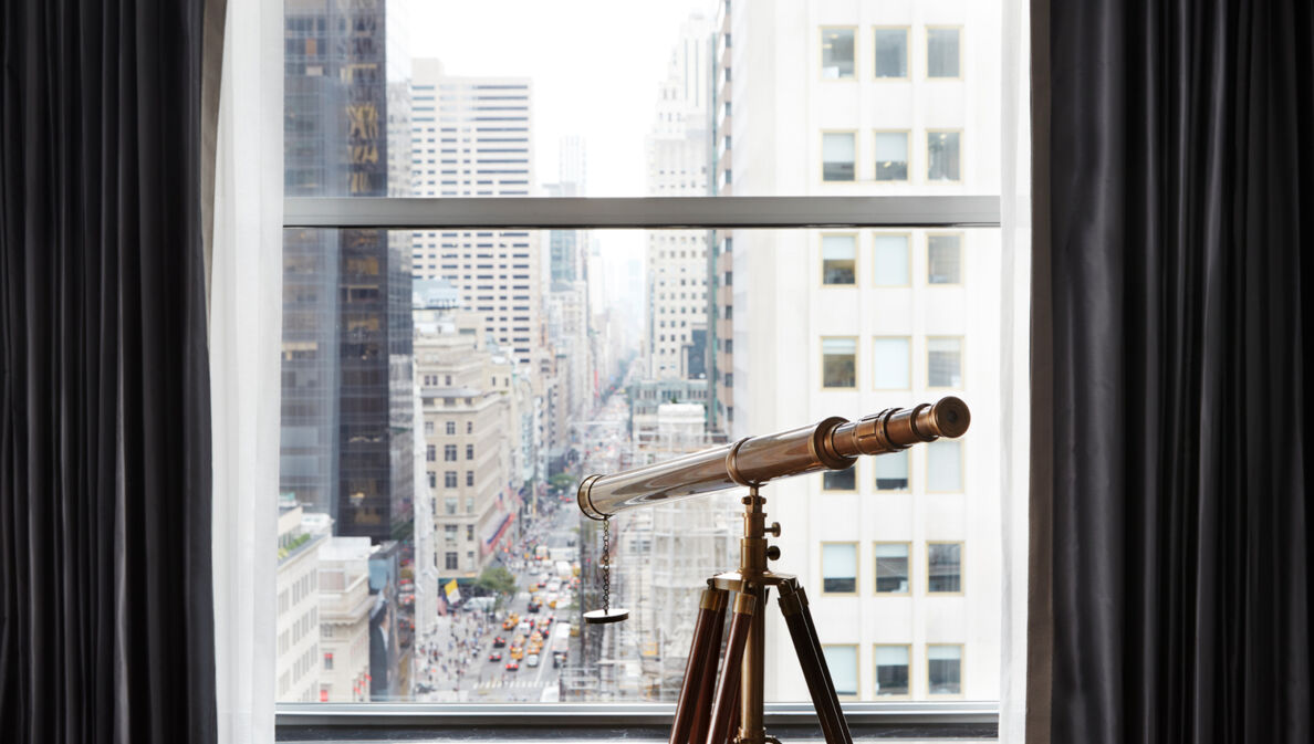 Blick durch ein Fenster auf die Fifth Avenue, am Fenster steht ein Fernrohr