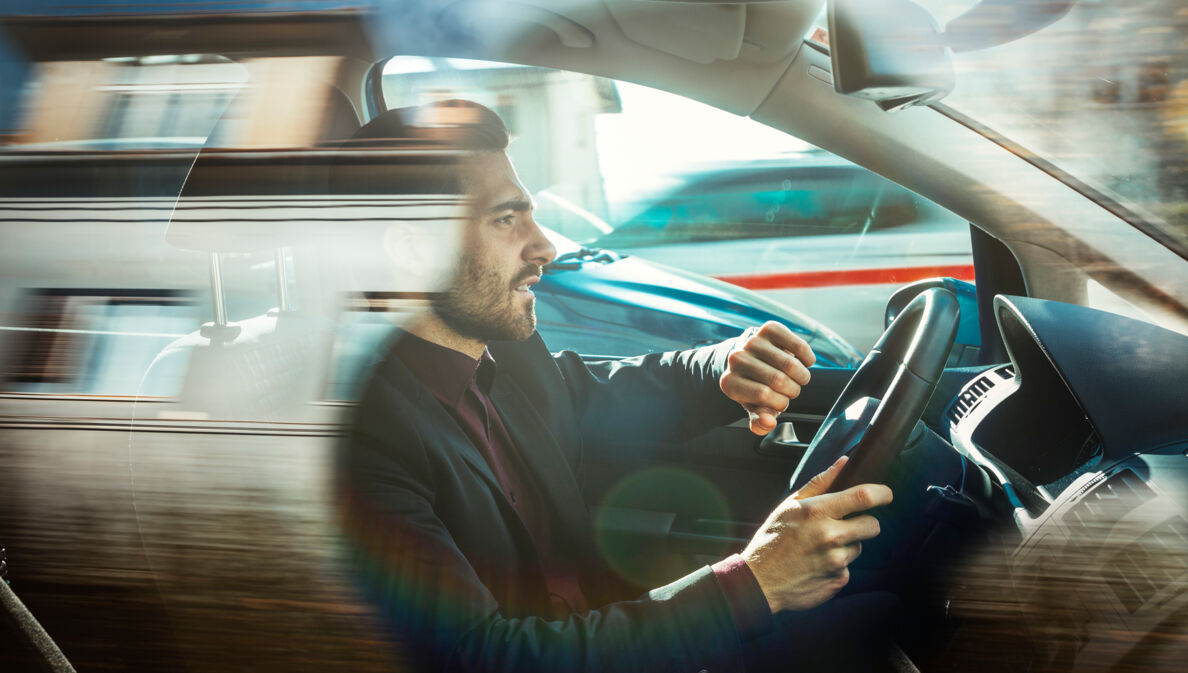 Ein Mann in einem Auto hebt seinen Arm, um auf die Armbanduhr zu schauen