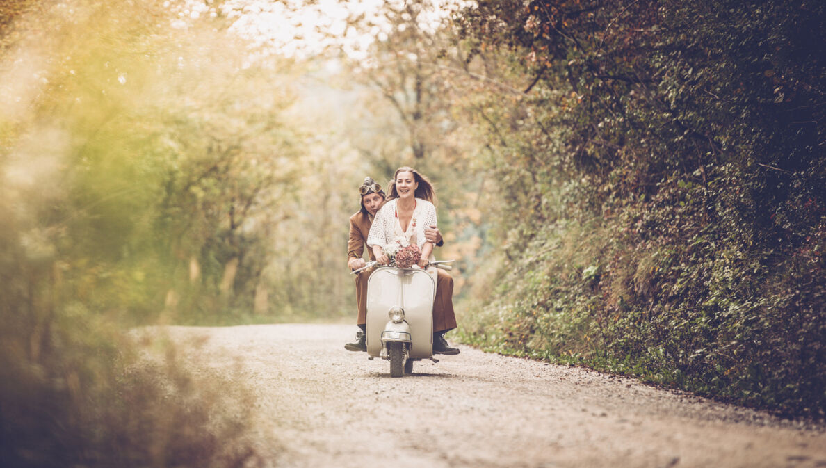 Ein junges Pärchen auf einer alten Vespa