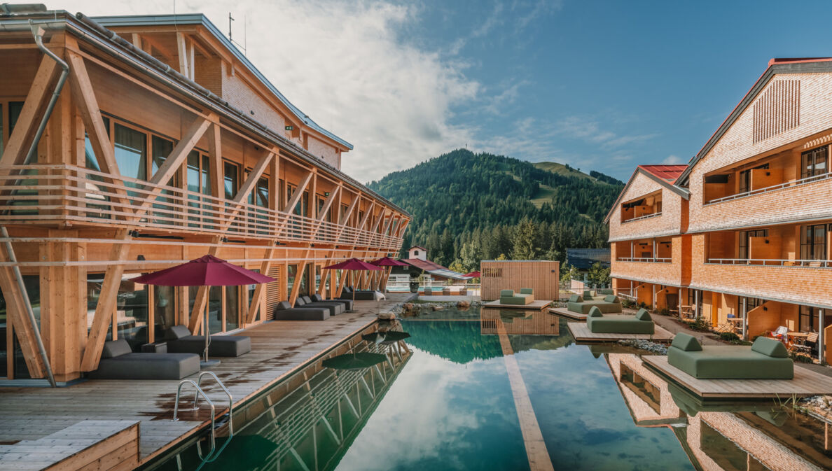 Ein Luxushotelanlage aus Holz mit Außenpool und Blick auf die Berge