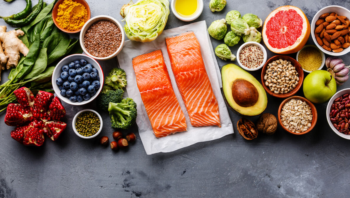 Gesunde Lebensmittel wie Lachs, Avocado, Granatapfel und mehr nebeneinander.