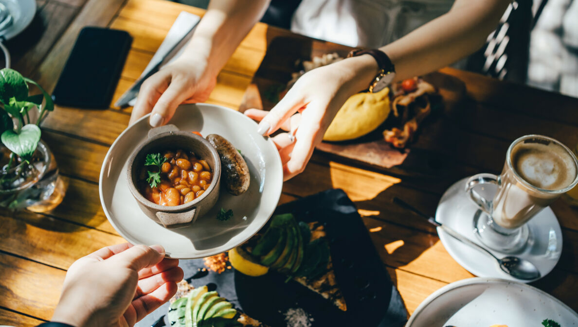 Hände reichen bei einem Brunch in Berlin eine Schale mit Essen