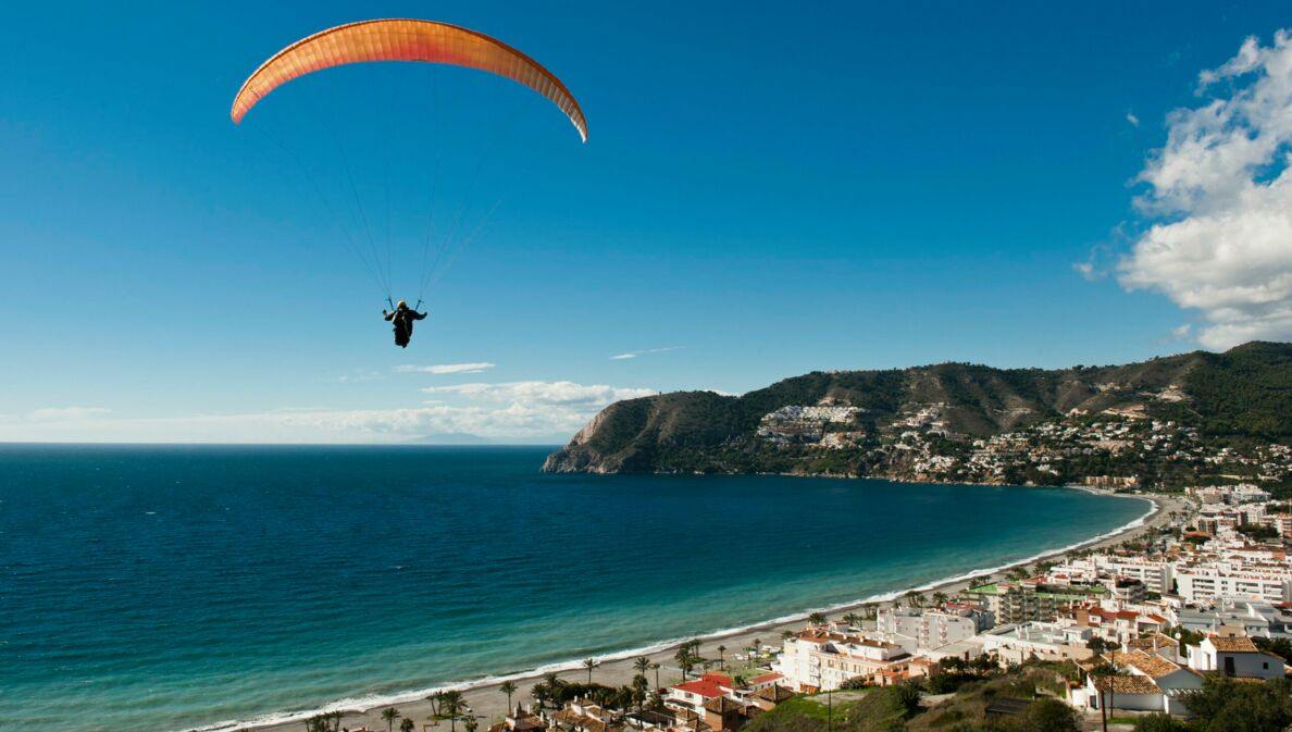 Ein Paraglider schwebt über einer Küstenstadt