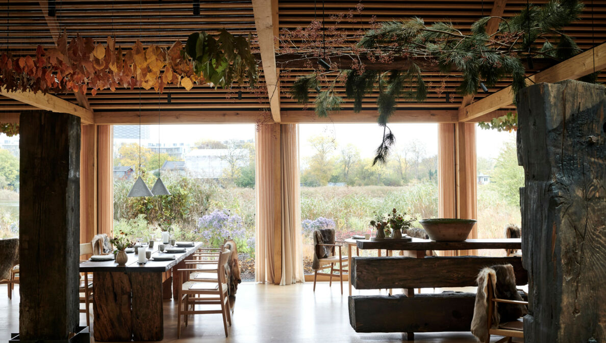 Innenraum eines Restaurants mit Blick nach draußen auf eine Wiese voller Wildblumen