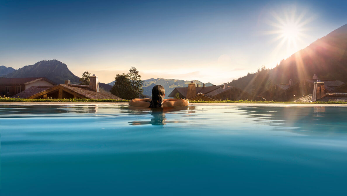 Rückansicht einer Person in einem Pool, im Hintergrund Berge