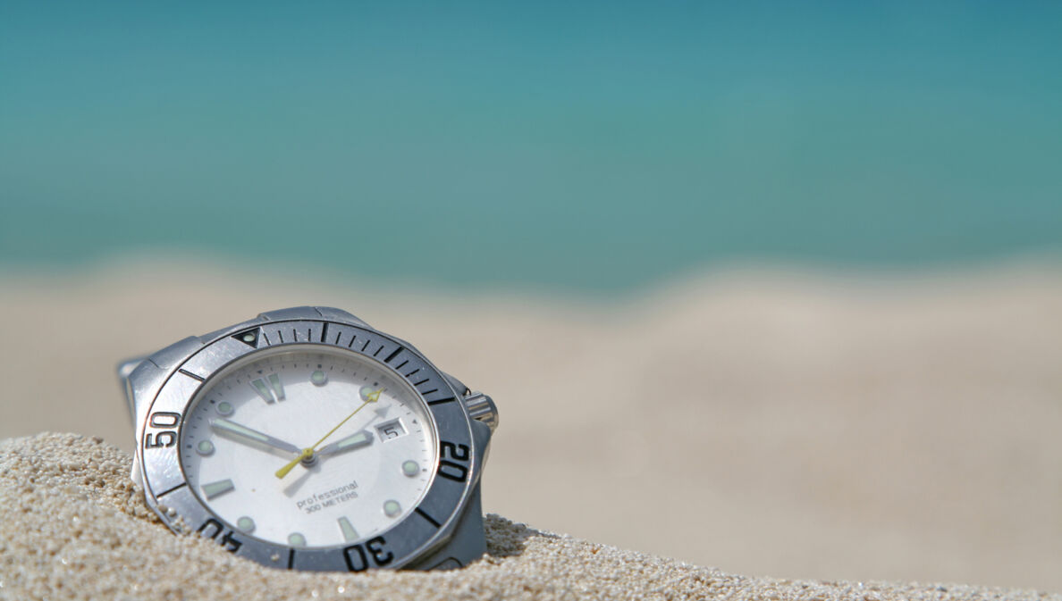 Taucheruhr mit Stahlgehäuse und weißem Zifferblatt in hellem Sand