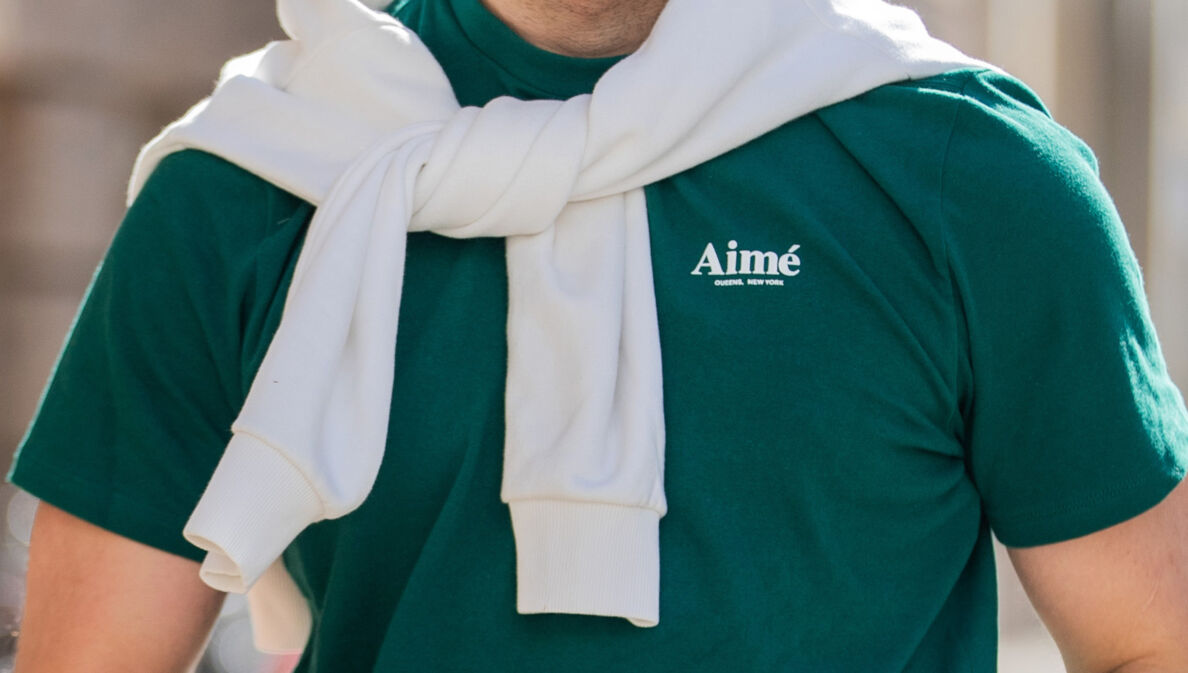 Oberkörper eines sportlichen Mannes in einem grünen T-Shirt mit dem Schriftzug der Marke Aimé