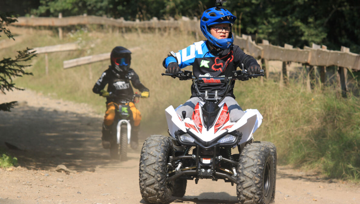 Ein Junge fährt auf einem E-Quad über unbefestigtes Gelände.