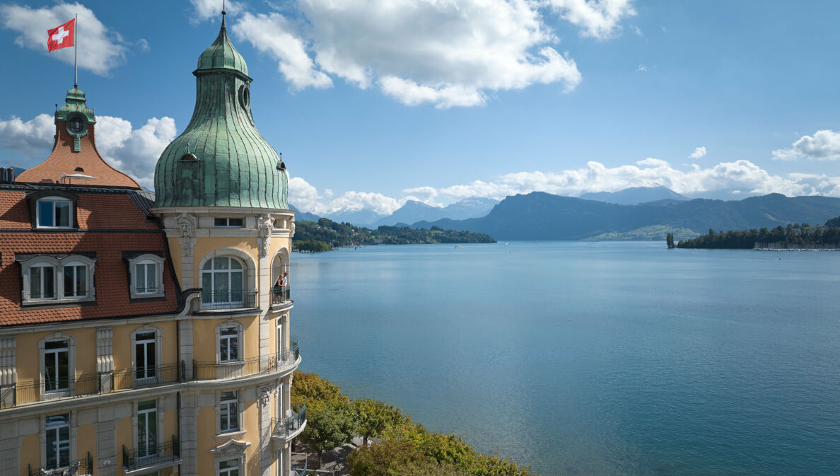 Hotel am See, im Hintergrund Berge und Wolken