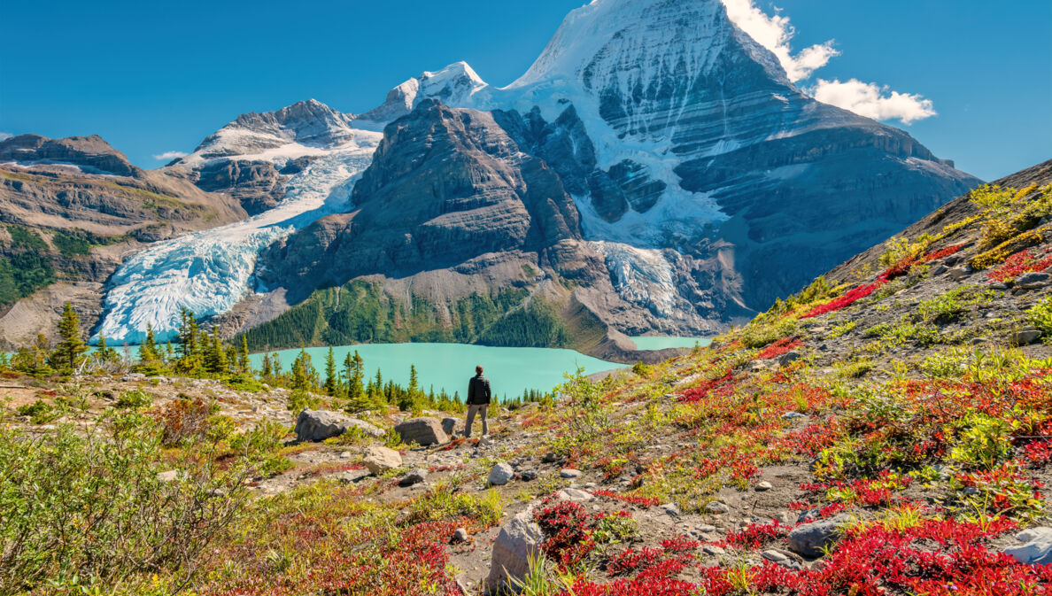 Ein Wanderer steht an einem See im Gebirge eines Nationalparks in Kanada