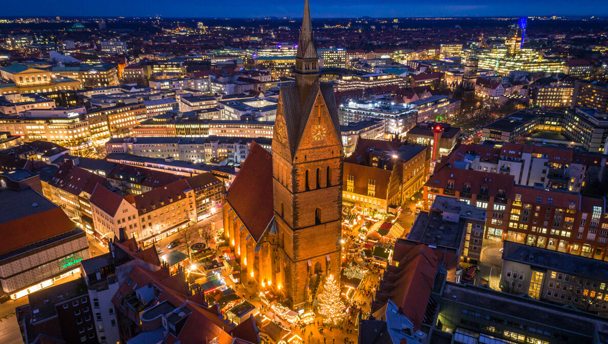 Blick von oben auf eine beleuchtete Stadt bei Nacht mit einer Kirche im Fokus