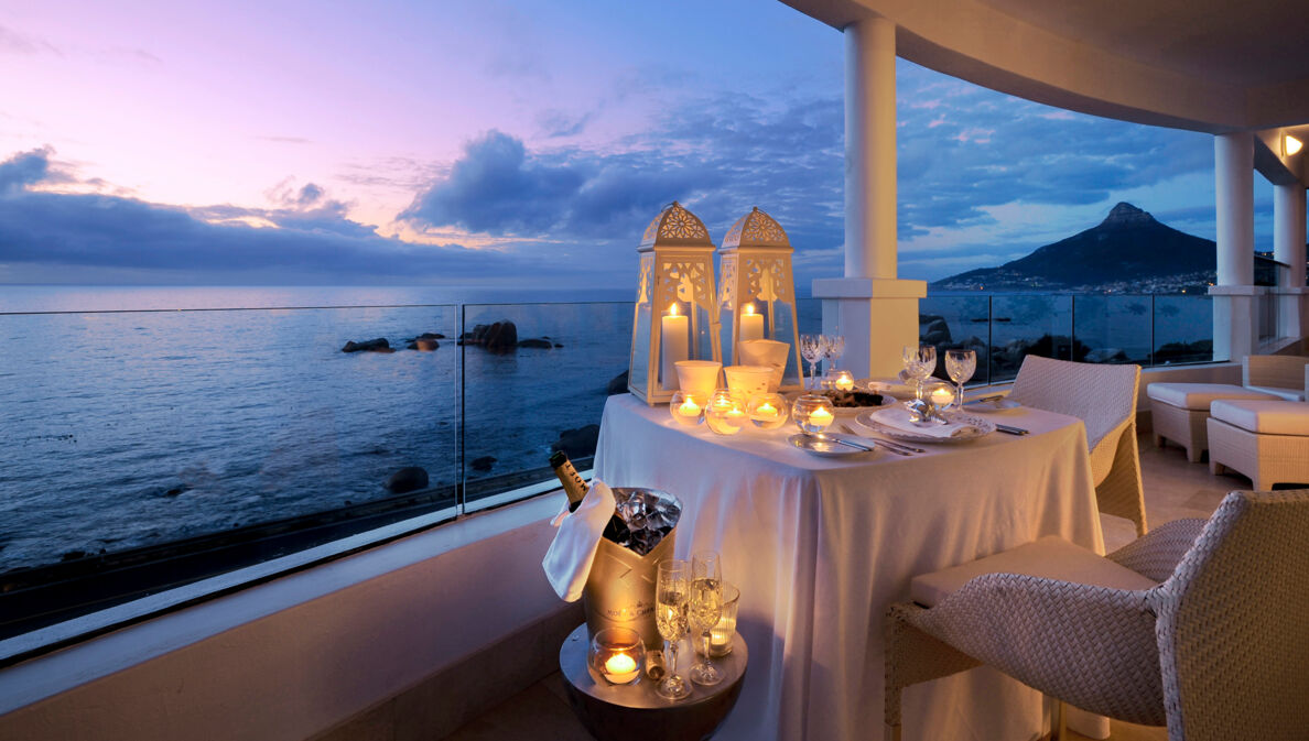 Große Terrasse einer Hotelsuite am Meer mit einem elegant gedeckten Tisch in der Abenddämmerung