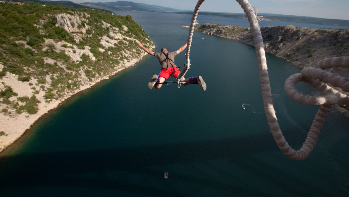 Eine Person springt an einem Bungeeseil in die Tiefe.